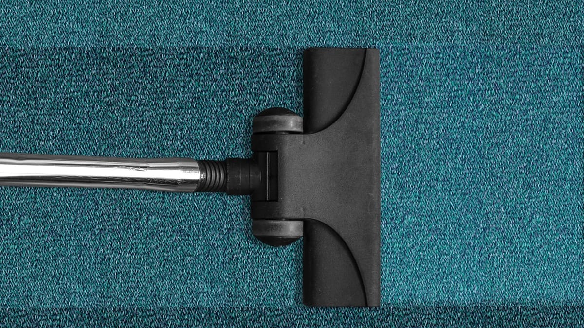 Brosse d'aspirateur noire posée sur une moquette bleu canard