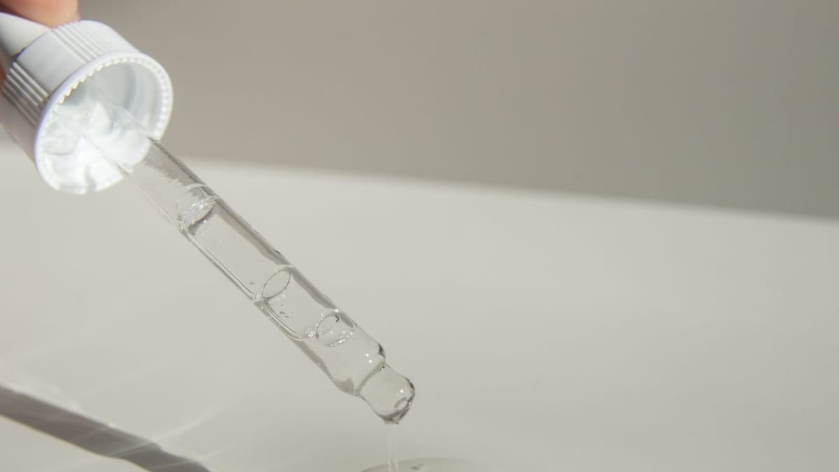 Pipette en verre déposant une goutte sur une surface claire